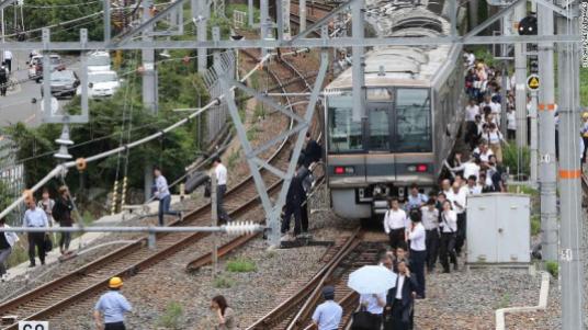 TOPSHOT - Passengers from a train walk along railroad tracks following an earthquake in Osaka on June 18, 2018. - A strong quake hit western Japan early June 18, but there were no immediate reports of major damage or risk of tsunami waves, officials said. (Photo by STR / JIJI PRESS / AFP) / Japan OUT (Photo credit should read STR/AFP/Getty Images)